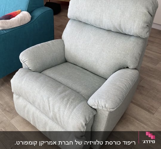 כורסה מרופדת בבד אפור בהיר על רצפת עץ